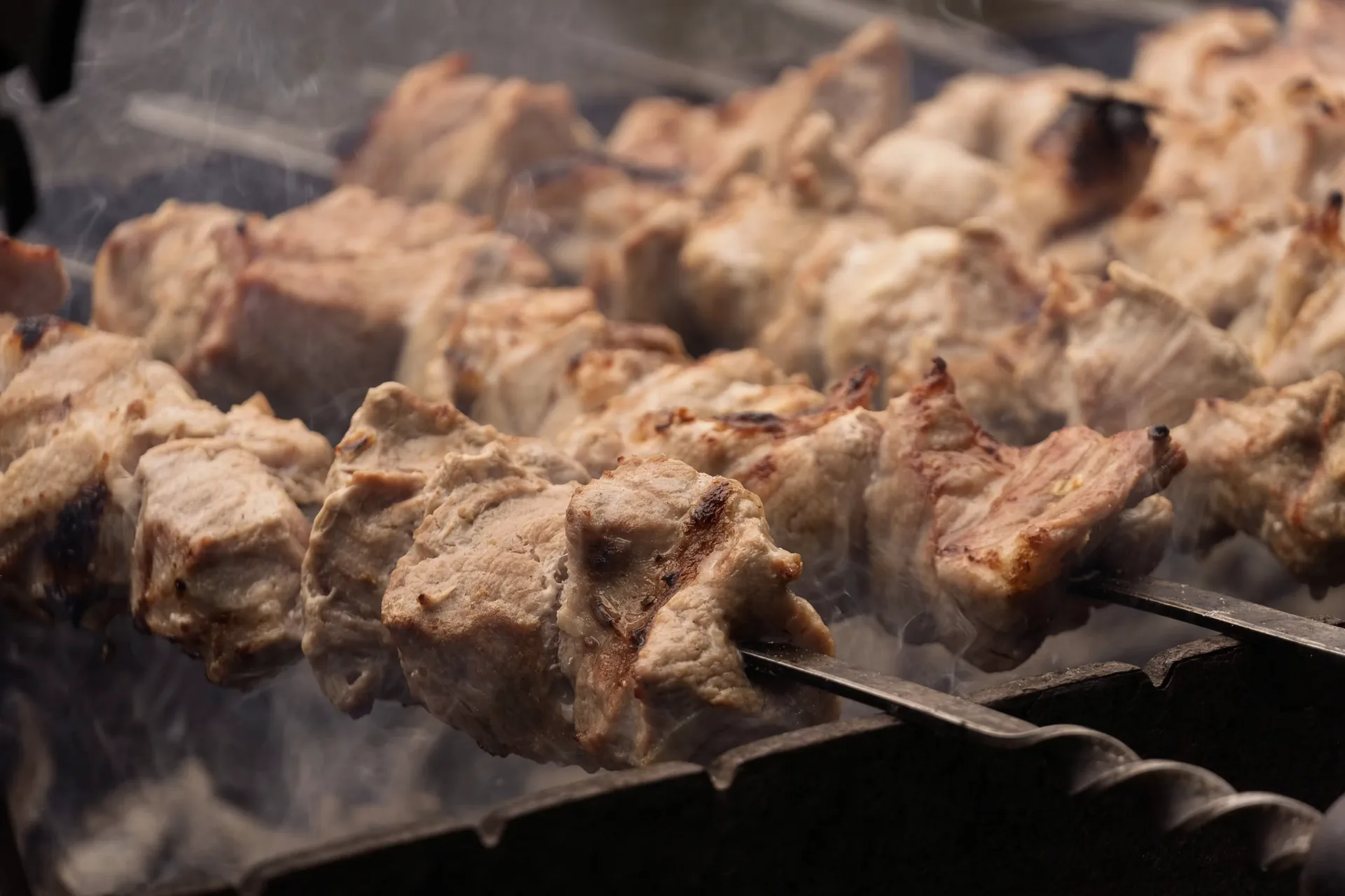 Meat skewers cooking over an open charcoal flame